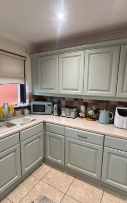 Green painted kitchen with grey worktops